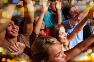 party, holidays, celebration, nightlife and people concept - group of smiling friends waving hands at concert in club